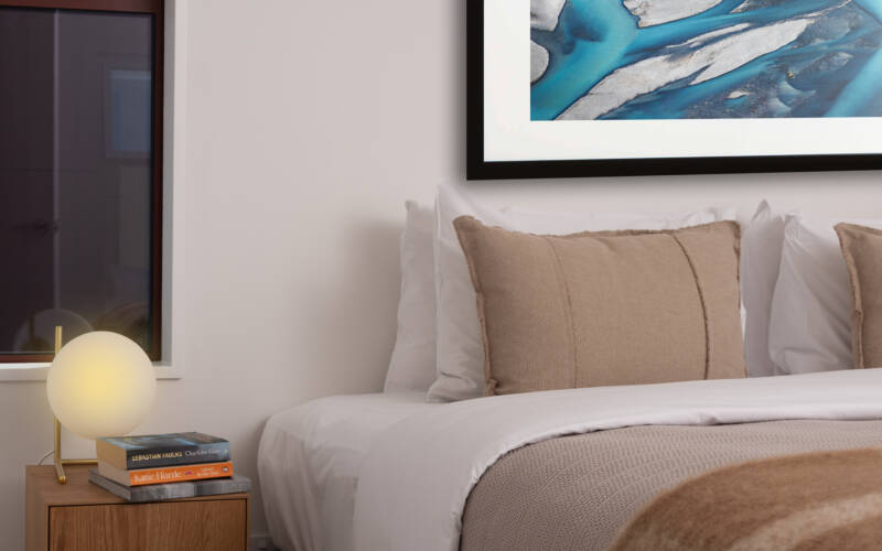 King bed with bedside light, and clock in the bedroom of a one-bedroom self-contained apartment at The Kilmore Collection, Christchurch.